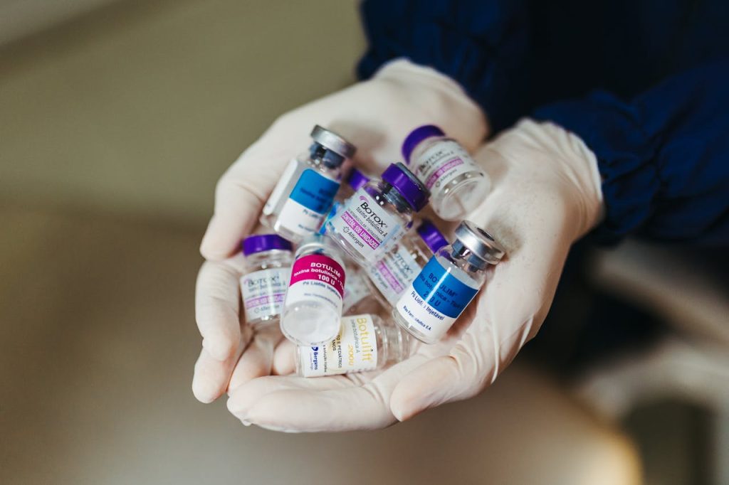 botox-flasks-on-doctor-hands-15688021 Close-up of gloved hands holding botulinum toxin vials in a laboratory, ideal for medical themes.